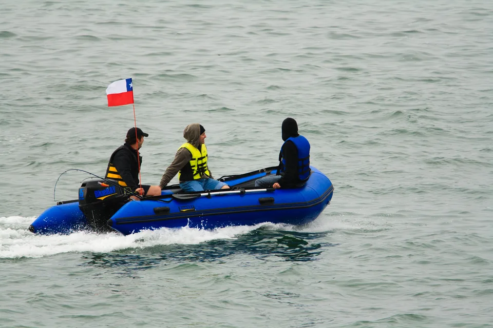 Bote azul navegando con tres personas