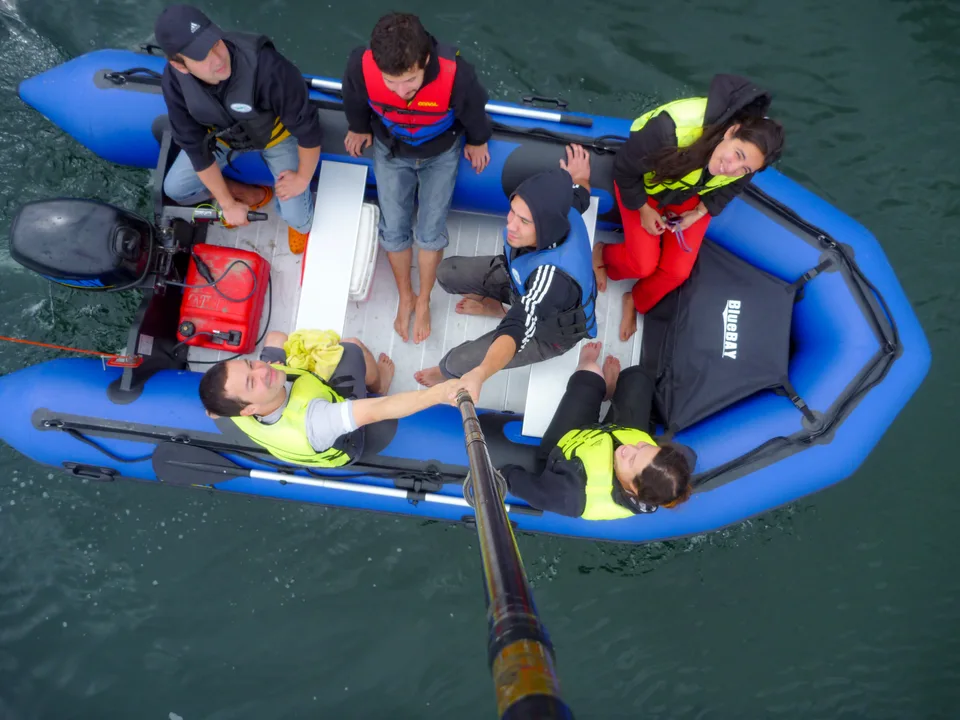 Tripulación con chalecos salvavidas en bote azul